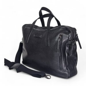 Black textured leather bag with two top handles and multiple zippers on a white background (bag viewed from side). Used as a shoulder/mest bag accessory.