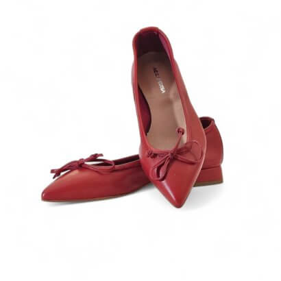 Red pointed-toe ballet flats with bow detail and tan insole viewed from above. It’s a pair of red leather flats with a front bow.