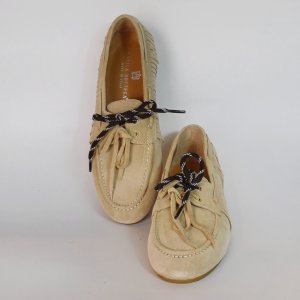 Beige suede boat shoes with black-and-white laces on a light surface, two shoes pictured together.