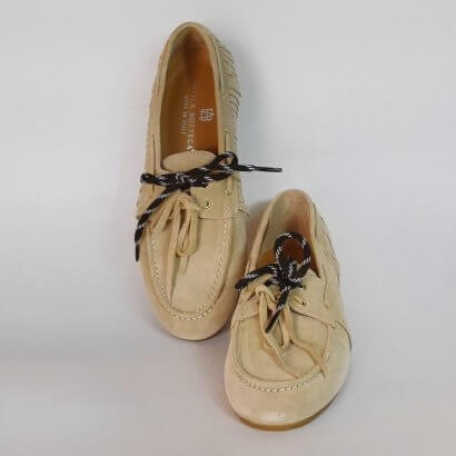 Beige suede boat shoes with black-and-white laces on a light surface, two shoes pictured together.