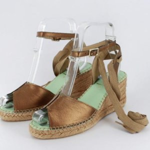 Brown leather wedge sandals with ankle straps and a braided jute sole on a light green insole. (Informative fashion footwear image)