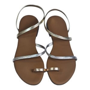 Top-down view of metallic silver strappy sandals on brown footbeds, showing multiple thin straps across the feet