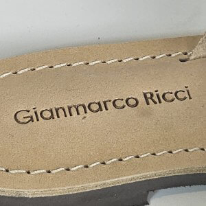 Close-up of a beige suede shoe sole with white stitching and the brand name 'Giammarco Ricci' embossed along the edge.